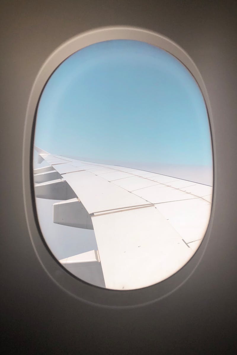 A clear view from an airplane window showing the sky and aircraft wing in daylight.
