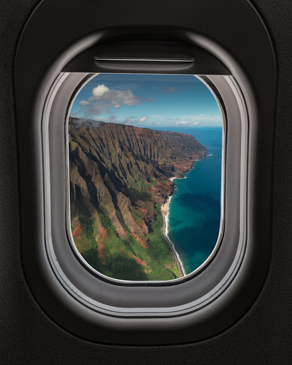Stunning aerial view of Na Pali Coast from an airplane window, showcasing Hawaii's natural beauty.